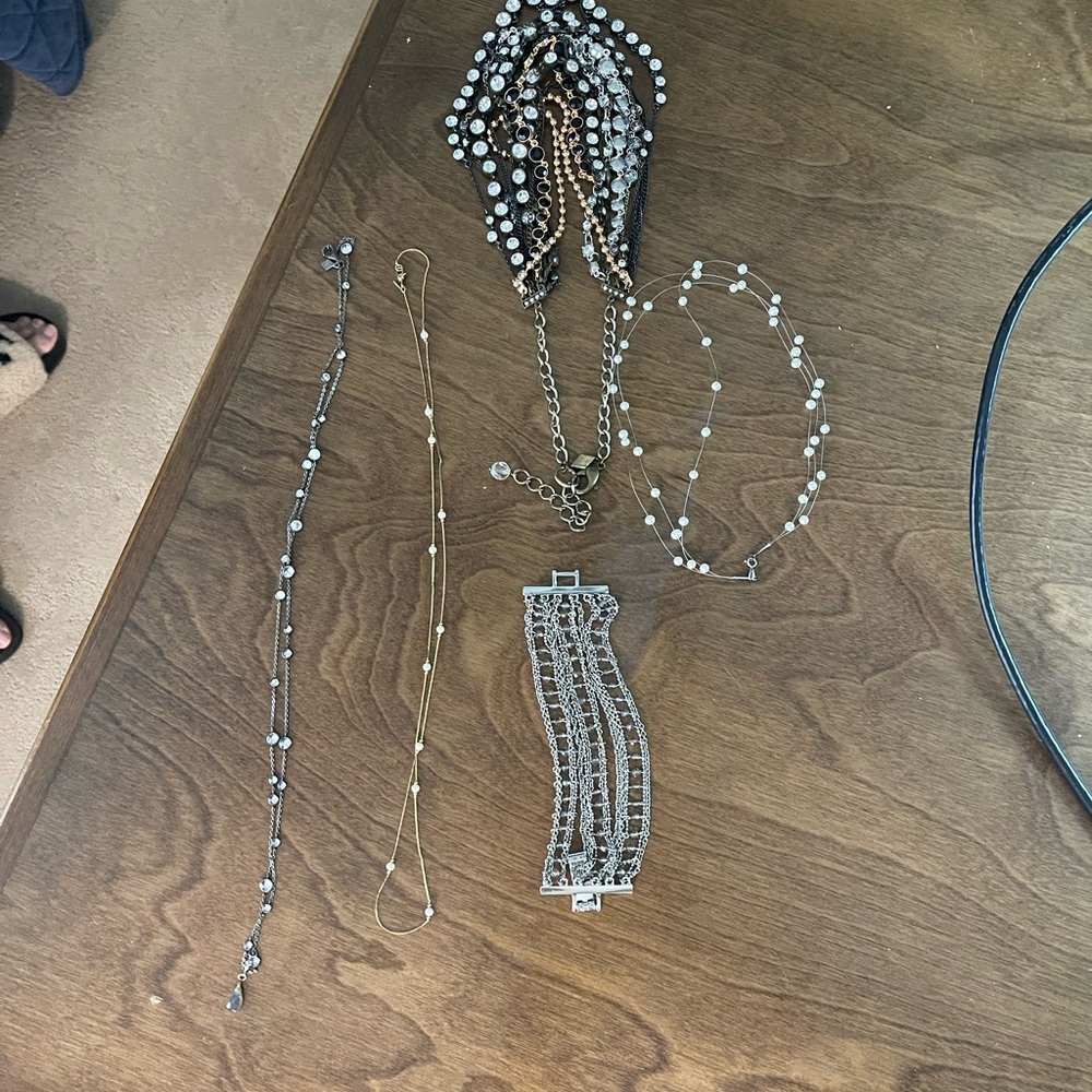 Five pieces of jewelry. One bracelet and four necklaces.